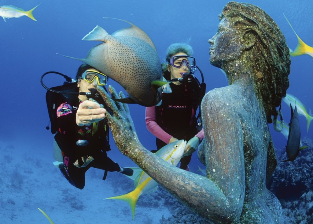 At home on the edge of Sunset Reef just off Sunset House is Amphritrite, the 9-foot bronze statue of a mermaid that has been featured on the cover of several dive magazines. The mermaid is one of the most recognized dive sites in the Cayman Islands. Photo courtesy Sunset House.